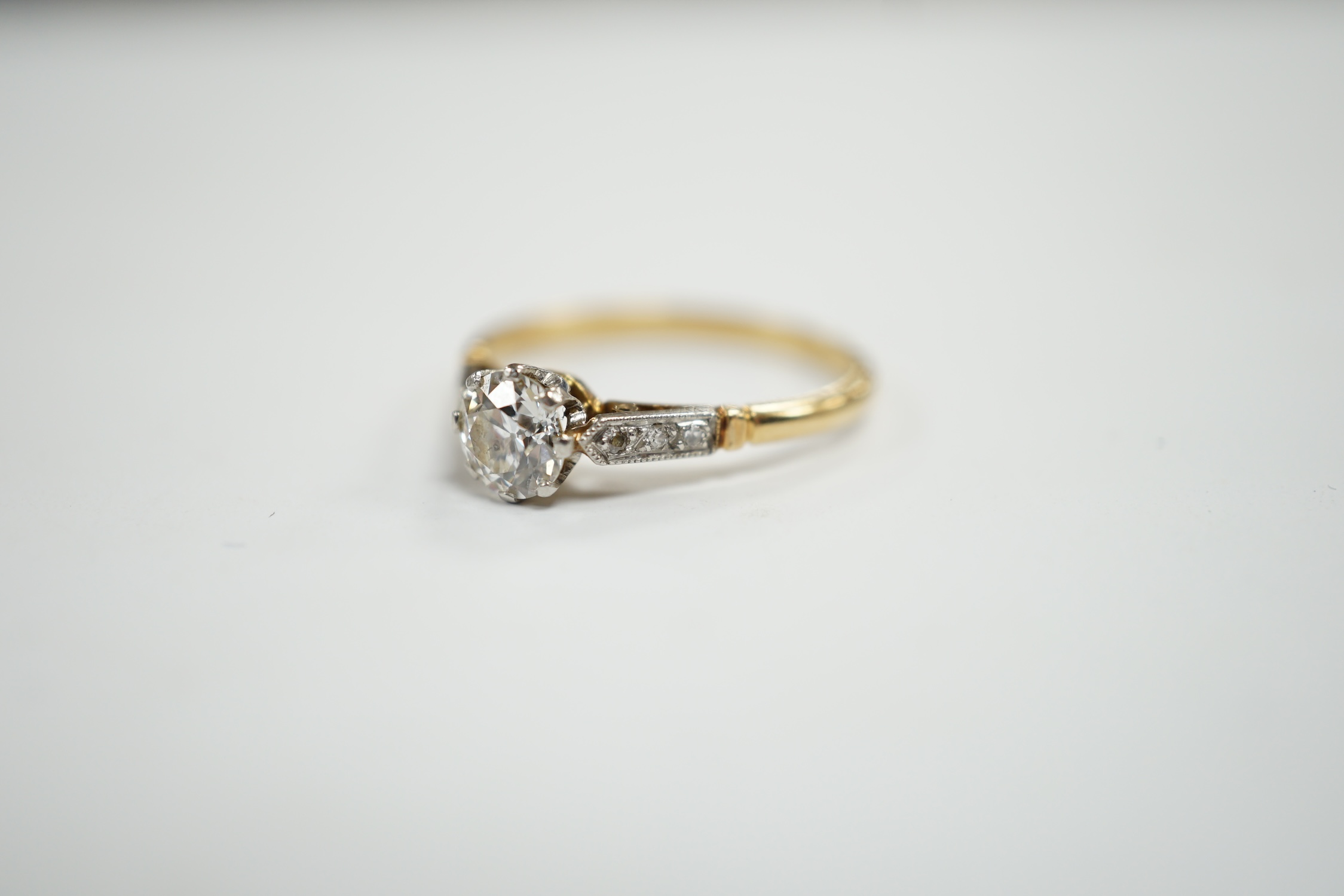 An early 20th century yellow metal and single stone diamond set ring, with diamond chip set shoulders, size N/O, gross weight 2.4 grams.